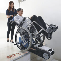Wheelchair King Una persona en silla de ruedas utiliza la [última máquina de escaleras para sillas de ruedas de tercera generación] con la ayuda de otra persona Wheelchair King es el agente exclusivo de la marca taiwanesa Yuanlun AIDBASE HKSC 970B para garantizar un acceso sin barreras.