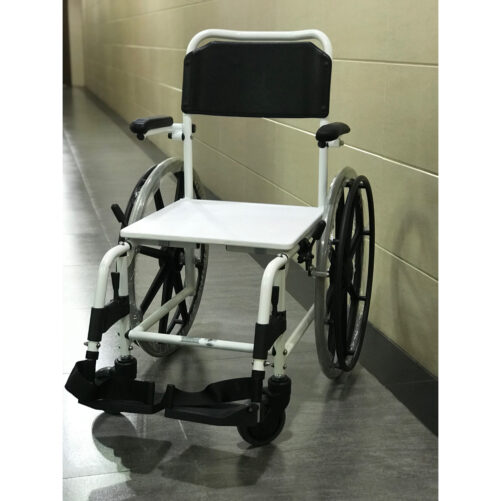 輪椅王 帶有黑色靠背的白色 Merits BR700 沖涼/坐便兩用輪椅放置在空蕩蕩的室內走廊中,米色牆壁和瓷磚地板。
