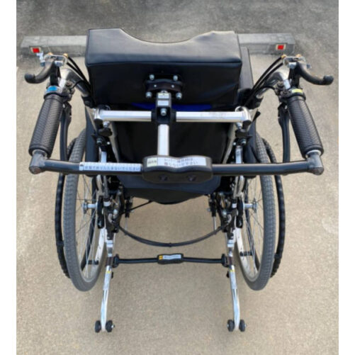 輪椅王 日本品牌Miki LX-2高背輪椅的後視圖具有黑色手柄、黑色座椅和金屬框架，全部位於混凝土表面上。