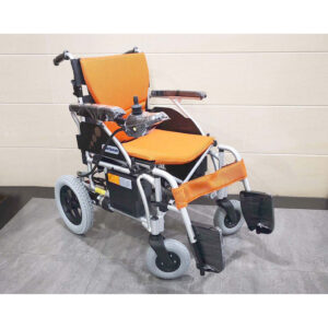 Le fauteuil roulant électrique léger et pliable de la marque taïwanaise Merits WP902 de Wheelchair King est livré avec un siège et un dossier orange, des accoudoirs noirs, des manettes de commande et des pédales, et repose contre un mur carrelé.