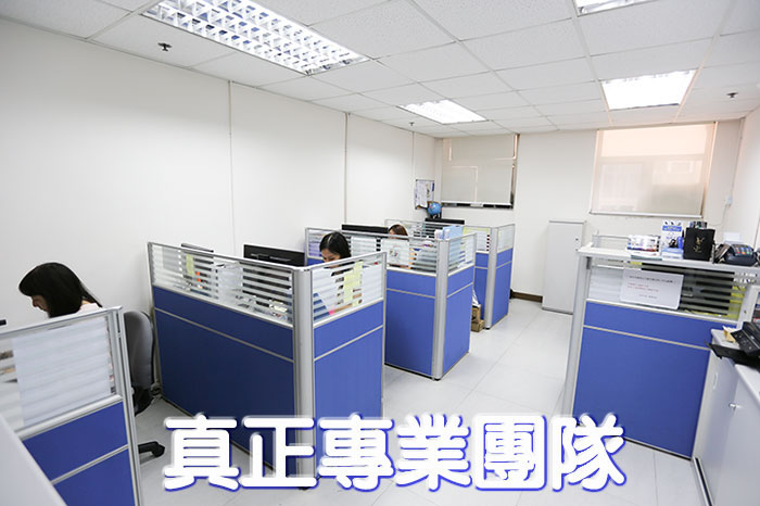 Wheelchair King An office with blue cubicles, where four people are working on computers. The walls are white and there are fluorescent lights on the ceiling. The Chinese text is the logo of "True Professional Team" (Professional Team) and Original Parts (Original Parts).