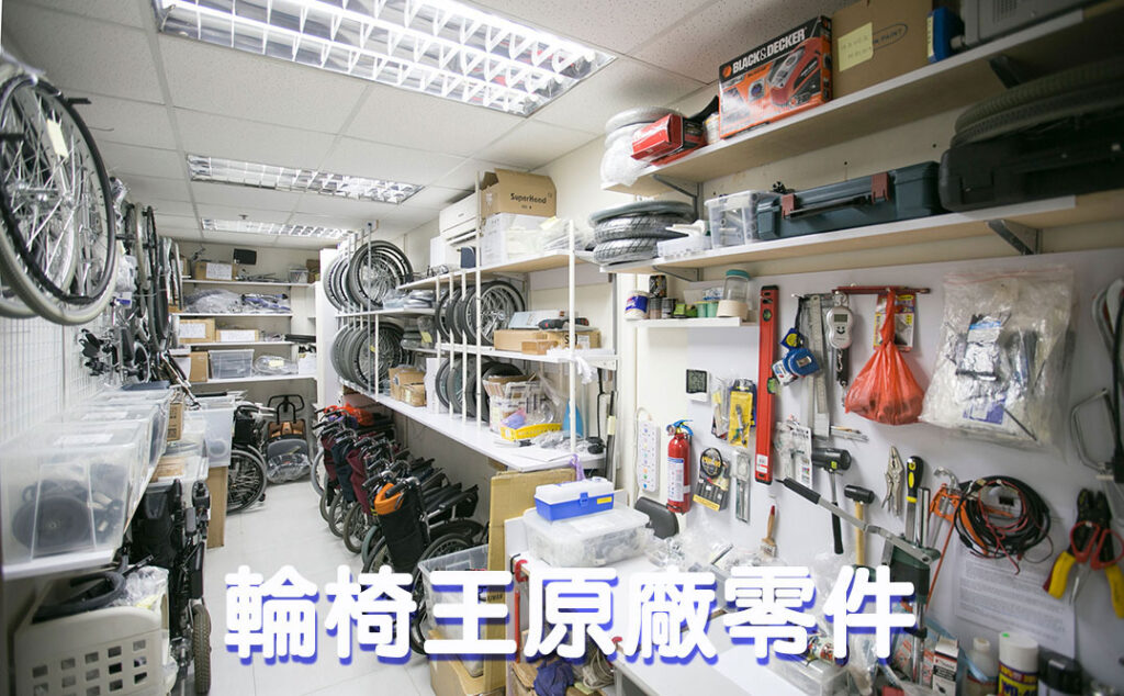 Wheelchair King’s messy workshop is filled with various wheelchair parts and tools, including tires, seat cushions and mechanical parts for wheelchair repairs. The shelves are filled with items, with a bicycle partially visible on the left.