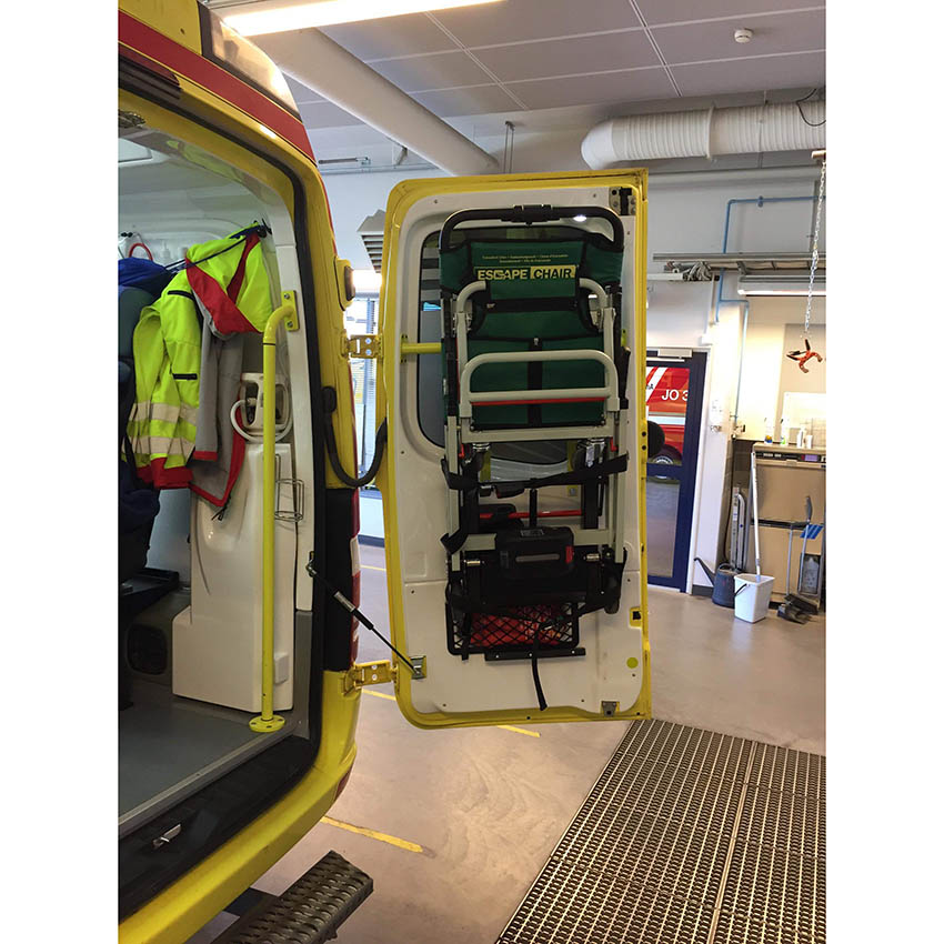 [ 輪椅王 ] 車庫裡一輛門開著的黃色救護車，配備電動樓梯疏散椅。