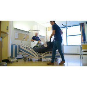 Wheelchair King Two medical staff take care of a person lying in a hospital bed in a room equipped with medical equipment and large windows.