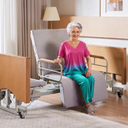 一位白髮老年婦女微笑著坐在家庭環境中的灰色可調式醫療椅上。