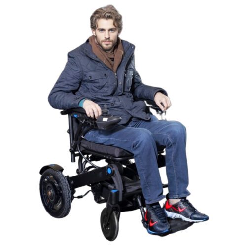 【車椅子の王様】青いジャケットとジーンズを着た男性が米国製サンシー・クイッキーQ50R型電動車椅子に座っている。日の出が彼の周囲に暖かい光を投げかける中、彼は右手で車椅子のコントロールを握りました。