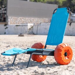 [Wheelchair King] Le fauteuil roulant de sable bleu Beach Star est distribué exclusivement par Wheelchair King et est produit en Turquie. Il est équipé de grandes roues orange et est situé sur le sable avec un fond rocheux.