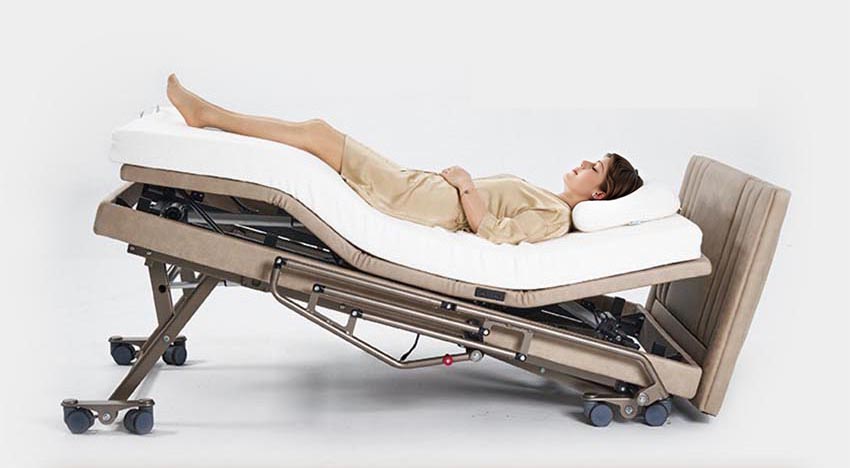 [Rey en silla de ruedas] Una persona se acuesta en una cama de hospital ajustable de una marca británica famosa por sus camas de enfermería inteligentes y multifuncionales. El modelo WCN931-Y cuenta con control remoto inalámbrico e incluye un colchón TPEE+ con capacidad de elevación total de la cama y ruedas fijadas al marco.