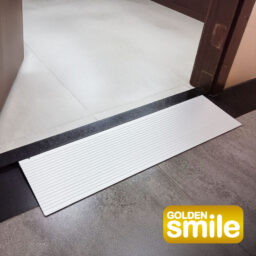 [Wheelchair King] The white ramp at the door provides a seamless transition between the two floor surfaces. The golden smile business board M03 logo is elegantly placed in the lower right corner.